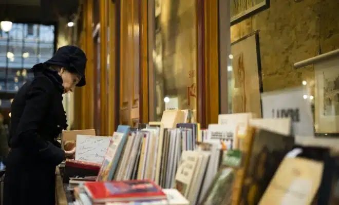 man in black cap standing in front of books